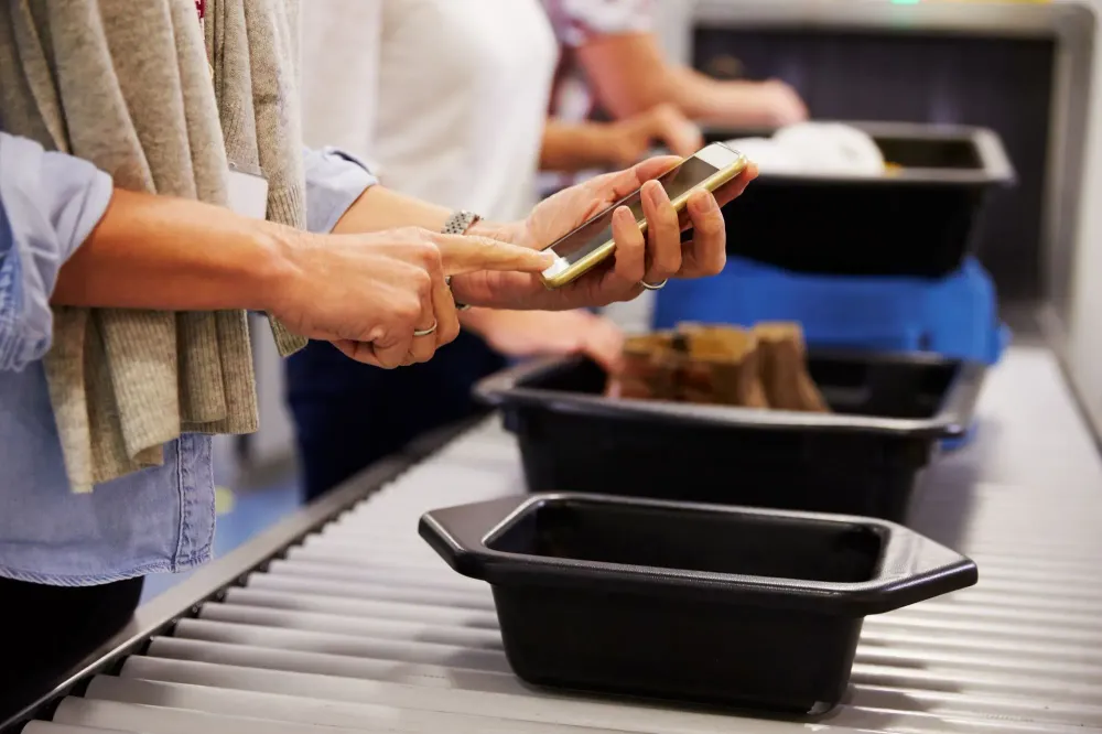 Person placing smartphone into bin at airport security